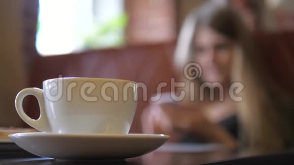 从白色咖啡杯转移焦点在年轻女子与电话视频的预览图