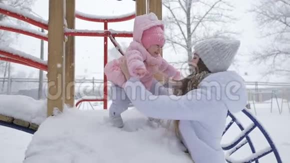 美丽的你妈妈和小女孩在公园的雪天视频的预览图