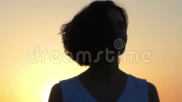 一个美丽的女人在斯隆莫的日落时转过头视频的预览图
