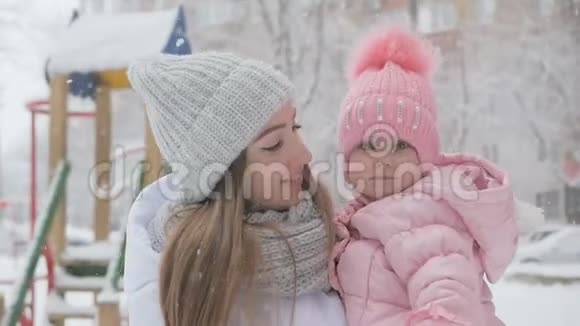 美丽的你妈妈和小女孩在公园的雪天视频的预览图