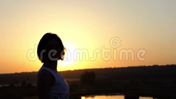 年轻的女人令人印象深刻地转动她的头和她的身体在日落时的蕾丝礼服在斯隆莫视频的预览图