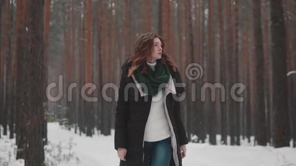 红发女孩在一场大雪下漫步在冬天的森林里慢动作视频的预览图