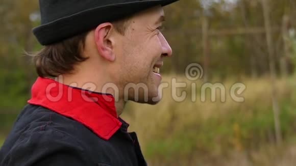 一个戴着黑帽子的年轻人站在森林里用邋遢的拇指向上做手势视频的预览图