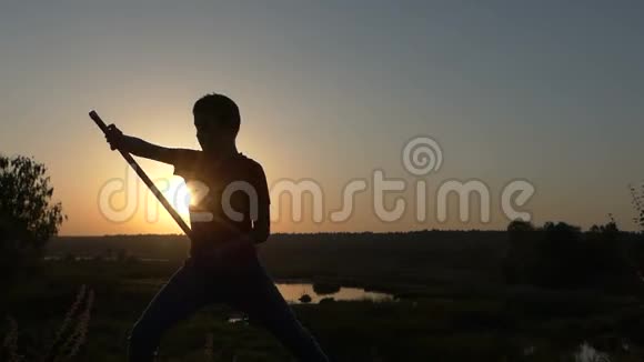 在夕阳下的湖岸上用棍子打功夫男孩的屁股视频的预览图