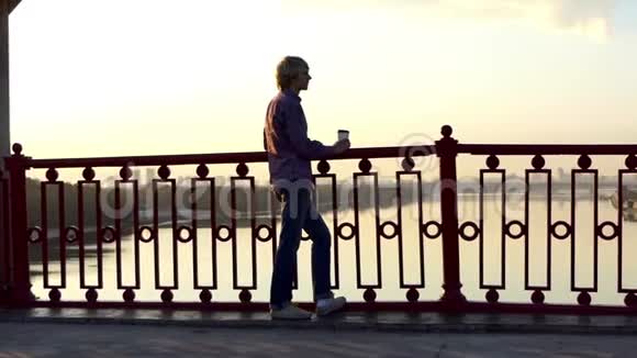 浪漫的男人喝咖啡在斯隆莫的桥上享受日落视频的预览图