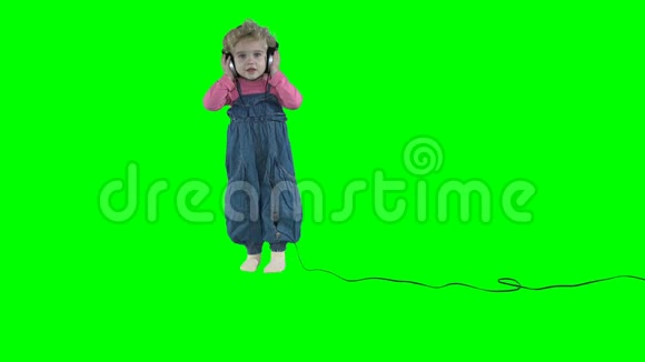 可爱的小女孩带着大耳机在绿色背景下跳舞视频的预览图
