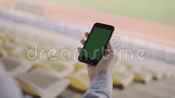 男子使用智能手机在体育场内看着手机上的绿色屏幕视频的预览图