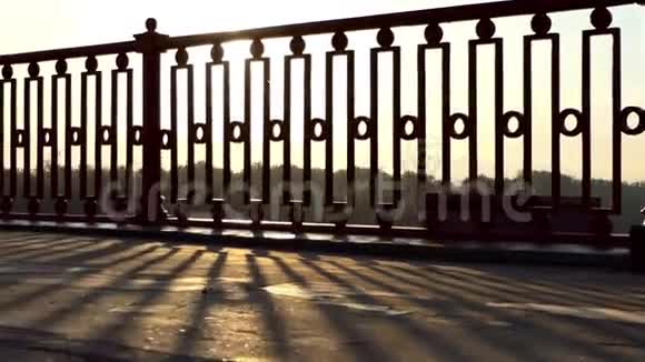 在夏日灿烂的夕阳下雄脚沿着现代的大桥移动视频的预览图