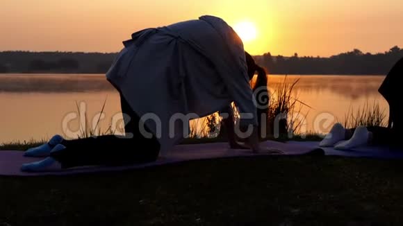 两个女人在斯隆莫的日落时做瑜伽的四人侧写中镜头视频的预览图