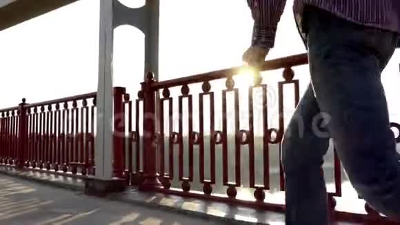 一个年轻人在日落时以慢动作跳舞的方式在桥上行走视频的预览图