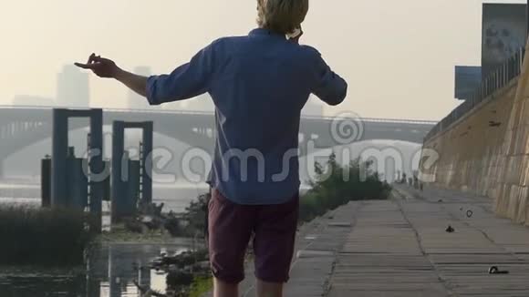 夏天在斯隆莫的河岸上年轻人用一辆移动的手势说话视频的预览图