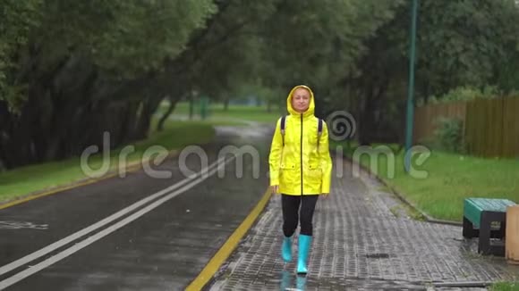 年轻漂亮的快乐女人穿着黄色雨衣享受着雨视频的预览图