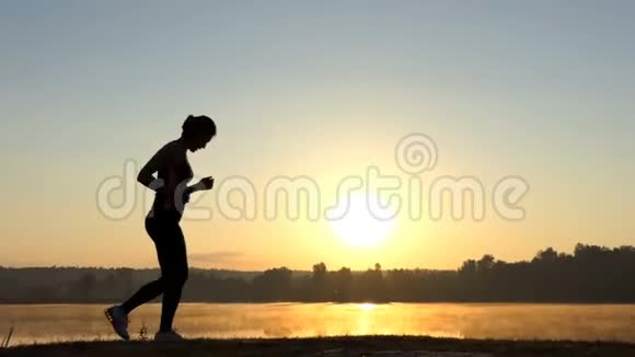 苗条的女人在日落时跑回来跳过去视频的预览图