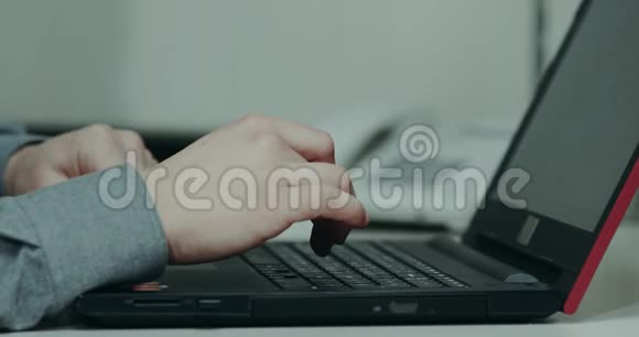 特写办公桌上的男人从笔记本电脑上敲击键盘视频的预览图