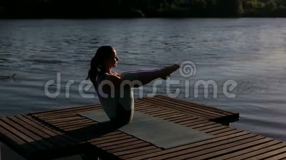 小女孩在池塘边练习瑜伽的剪影视频的预览图