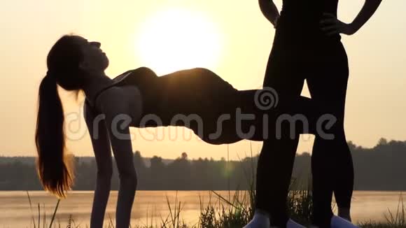 年轻的孕妇在4k的日落时保持她的腹部做瑜伽视频的预览图