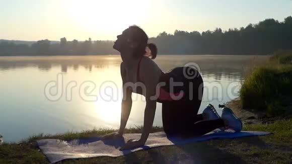 一个运动的女人在湖岸四周训练瑜伽视频的预览图