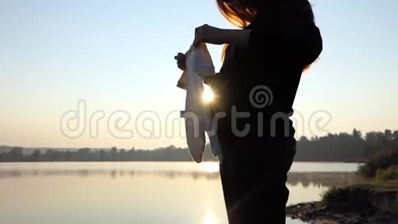 一位孕妇在日落时将婴儿身上的衣服放在腹部视频的预览图