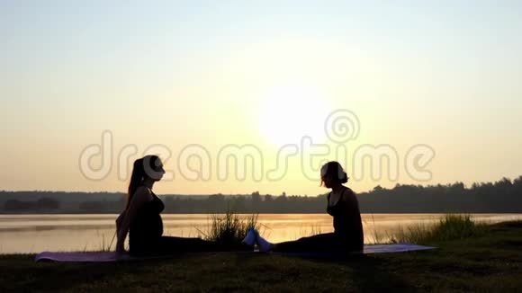 4k两位女士坐在湖岸日落时做瑜伽表演视频的预览图
