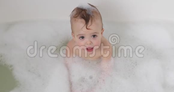 婴儿在充满泡沫的浴缸里向上看视频的预览图