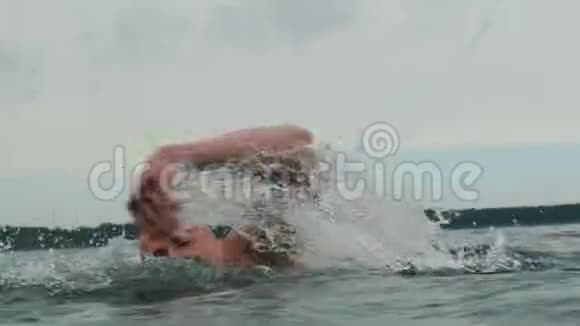 英俊的白种人男子游泳在湖外侧观4k视频的预览图