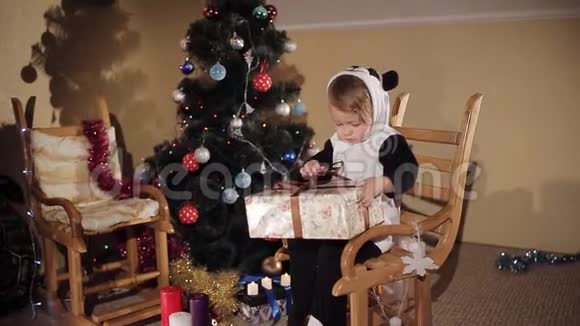 穿着熊猫服的孩子在圣诞树旁打开圣诞礼物视频的预览图