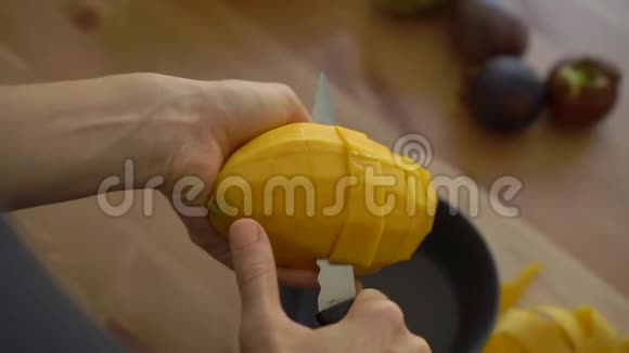 慢镜头一位年轻女子将芒果切成小块许多热带水果摆在桌子上视频的预览图