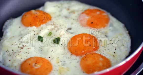 厨师准备煎蛋用黄油煮用盐和黑胡椒调味用小红盘煮绿洋葱视频的预览图