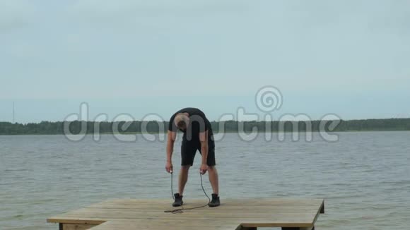肌肉运动员在湖边用跳绳运动的肖像视频的预览图