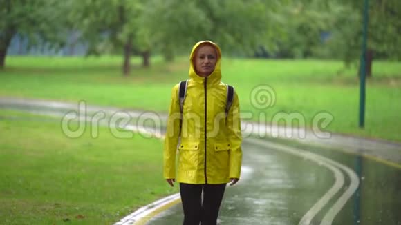年轻漂亮的快乐女人穿着黄色雨衣享受着雨视频的预览图