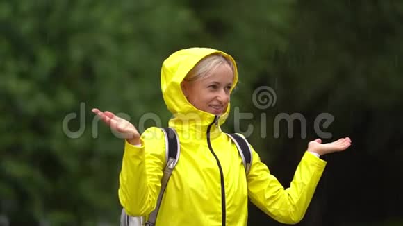 年轻漂亮的快乐女人穿着黄色雨衣享受着雨视频的预览图