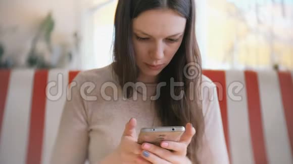 年轻漂亮的黑发女人打电话在咖啡馆里用手机等着回答等着她的朋友视频的预览图