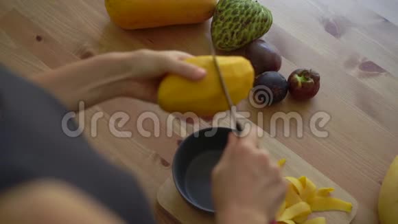 慢镜头一位年轻女子将芒果切成小块许多热带水果摆在桌子上视频的预览图