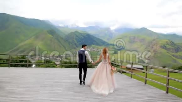 新婚快乐的新婚夫妇在他们的婚礼上在群山的背景下结婚照会格鲁吉亚视频的预览图