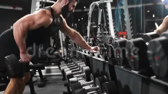 强壮的人在健身房锻炼肌肉用哑铃做力量练习健身俱乐部的运动员白种人视频的预览图