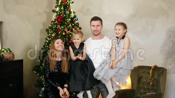 慢镜头拍摄四口小幸福的一家人在圣诞树上抛起金色的纸屑可爱的母亲父亲和视频的预览图