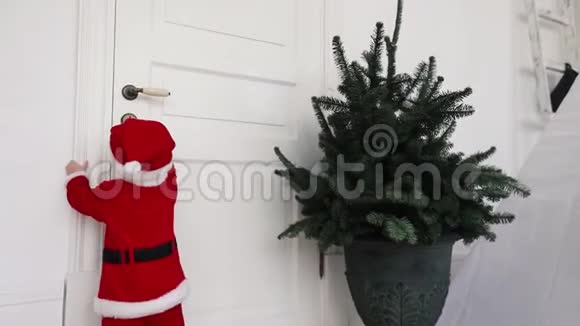 穿着圣诞服装的小孩试图打开家的门视频的预览图