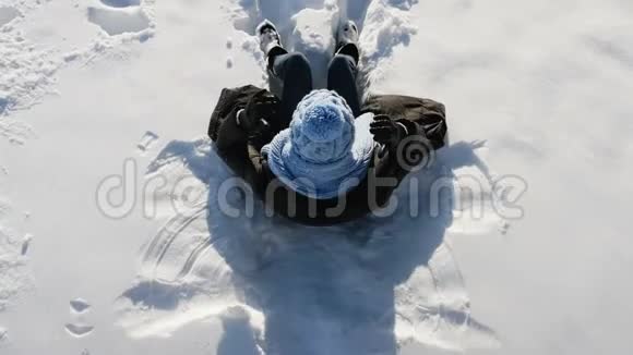 女孩戴着蓝帽子躺在雪地上视频的预览图