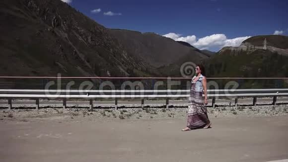 美丽的女孩走在山里的路上梳着头发视频的预览图