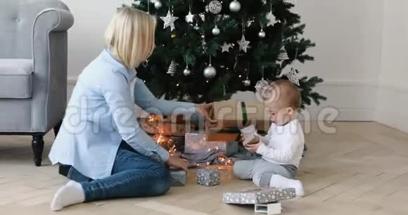 妇女和儿童在圣诞树下打开礼物视频的预览图