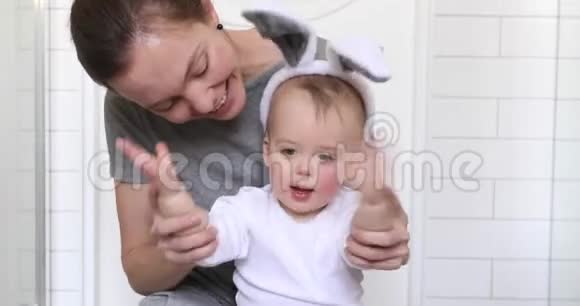 快乐的妈妈带着穿着兔子服装的宝宝视频的预览图