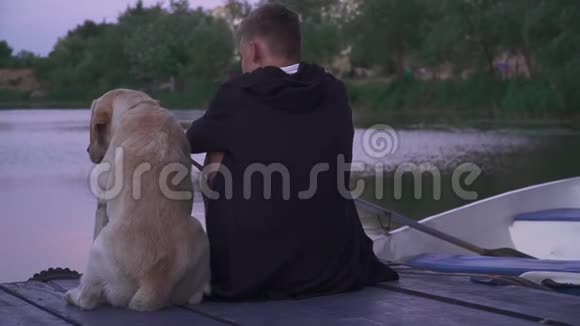 湖边码头上有条狗的年轻人视频的预览图