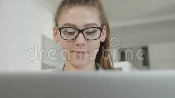年轻的女学生在家里使用笔记本电脑在社交网络上聊天微笑着视频的预览图