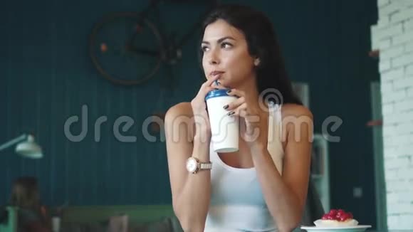 一位年轻迷人的女士在咖啡店喝着纸杯里的咖啡视频的预览图