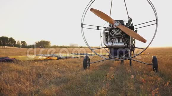汽车滑翔伞在日落时分用木制螺旋桨站在田野里飞行员伸出降落伞视频的预览图