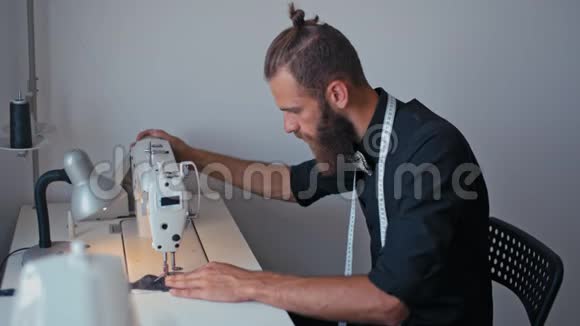 帅气的大胡子裁缝正在为他的时尚创业做缝纫机视频的预览图