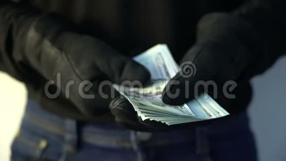 犯罪概念男子戴黑色皮手套拿着一堆钱视频的预览图