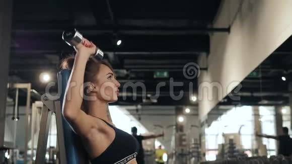 一位年轻的运动女性用哑铃来增强肌肉在室内健身房训练一位带杠铃的女孩视频的预览图