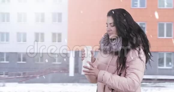 一个穿着冬衣的年轻女人去喝热杯里的茶视频的预览图