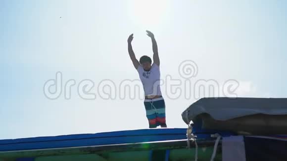在阳光明媚的日子里一个男人在蹦床上跳着不可思议的杂技表演视频的预览图